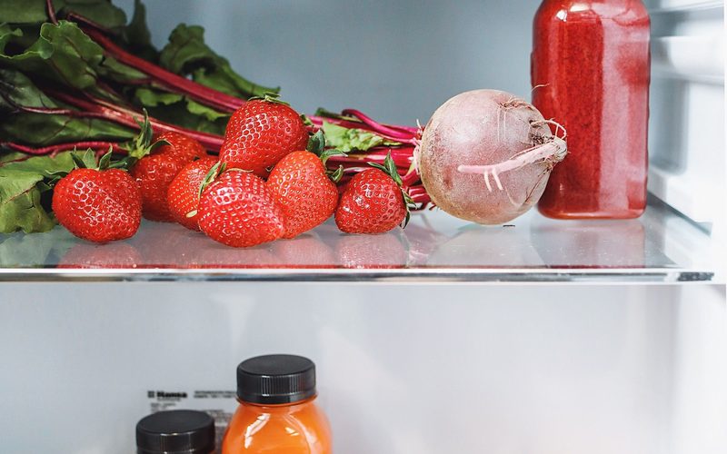Fresh vegetables and drinks stored on a clean refrigerator shelf