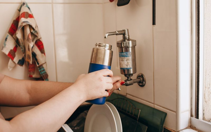 Hands replacing the filter cartridge of a wall mounted RO water purifier