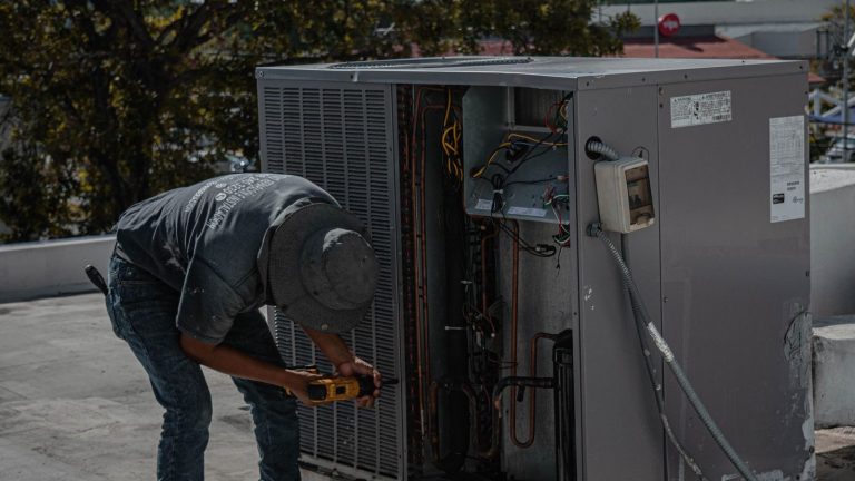 Technician servicing an air conditioner outdoor unit